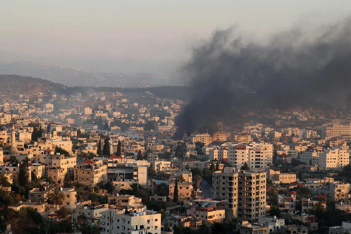 Smoke billows from houses inside a refugee camp in the West Bank city of Jenin on July 3, after an Israeli strike.