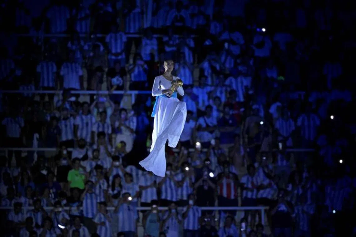 A hovering aerialist presents a replica World Cup trophy during a recognition ceremony after the friendly football match between Argentina and Curacao at the Madre de Ciudades stadium in Santiago del Estero, in northern Argentina on March 28, 2023. 