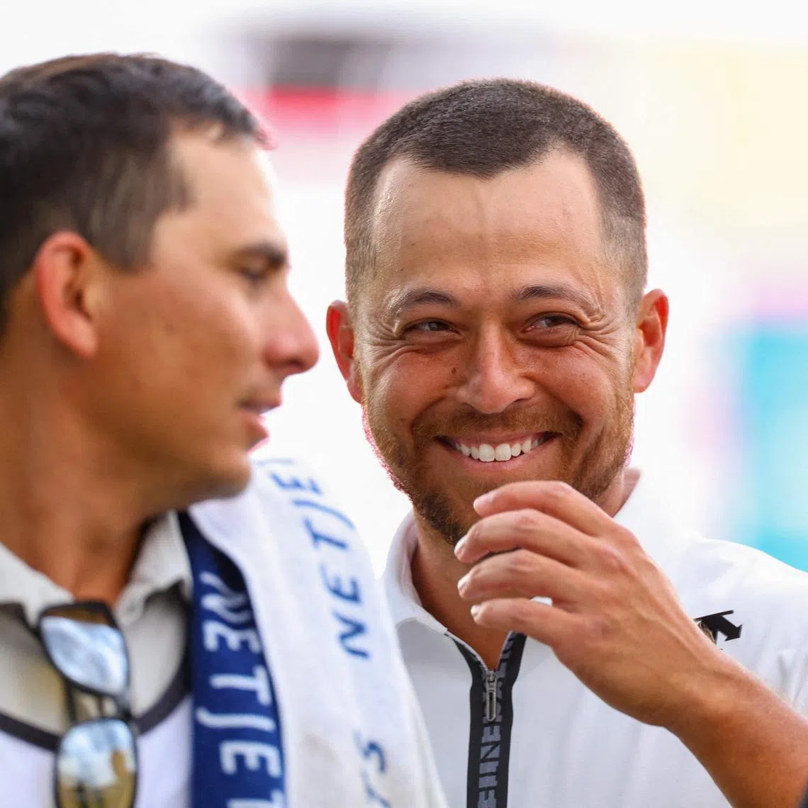 Xander Schauffele laughs with his caddie Austin Kaiser as they walk off the 18th hole after finishing the second round of the Wells Fargo Championship at Quail Hollow Country Club on May 10, 2024.