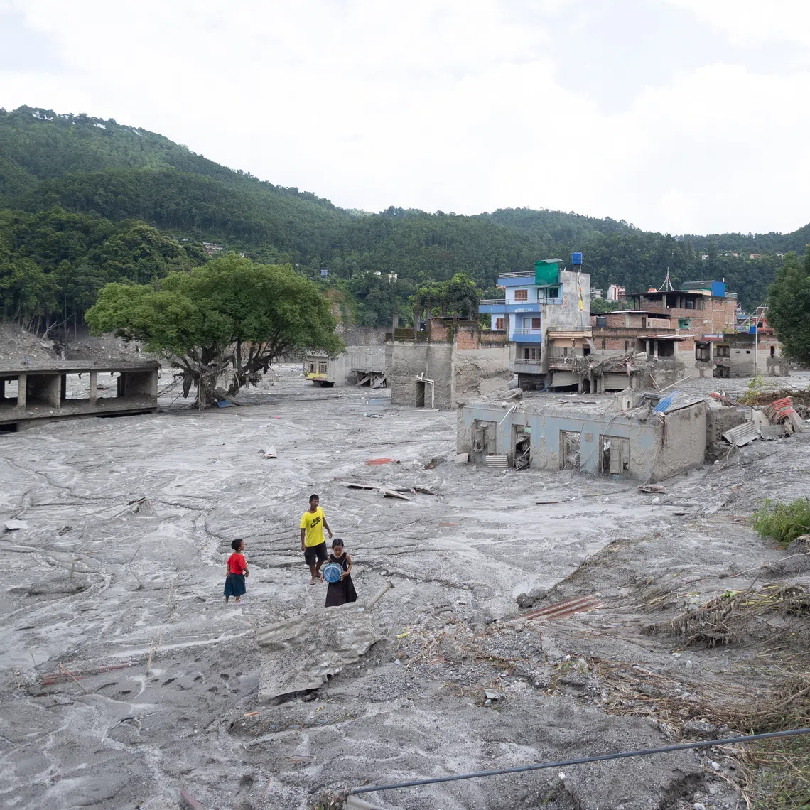 Children walk among buildings impacted by a glacial flood near the Nepal-China border that killed hundreds, in Trishuli Bazar, Nuwakot, Nepal, on Aug 31.