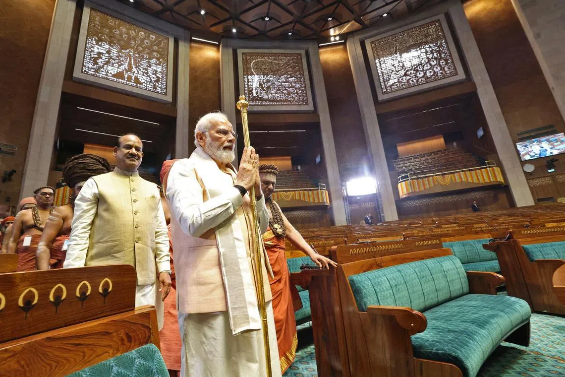 Indian PM Narendra Modi carries a sengol as Speaker of the Lok Sabha Om Birla looks on during the inauguration of new Parliament building in New Delhi.