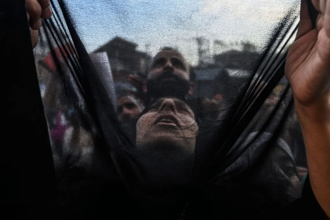 A Muslim devotee offering prayers as a priest displays a relic marking the 'Urs', or the death anniversary of the Sufi saint Sheikh Abdul Qadir Jeelani, at his shrine in Srinagar, on Oct 5, 2025. 