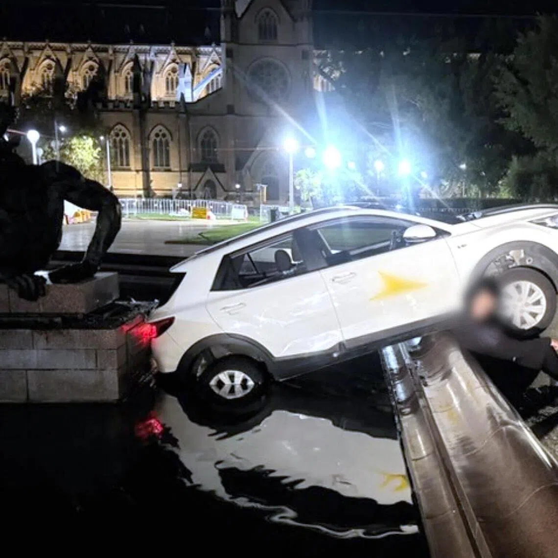 A police officer talks to a 21-year-old Frenchman who allegedly crashed an SUV car into the Archibald Fountain in downtown Sydney's Hyde Park on June 3. 