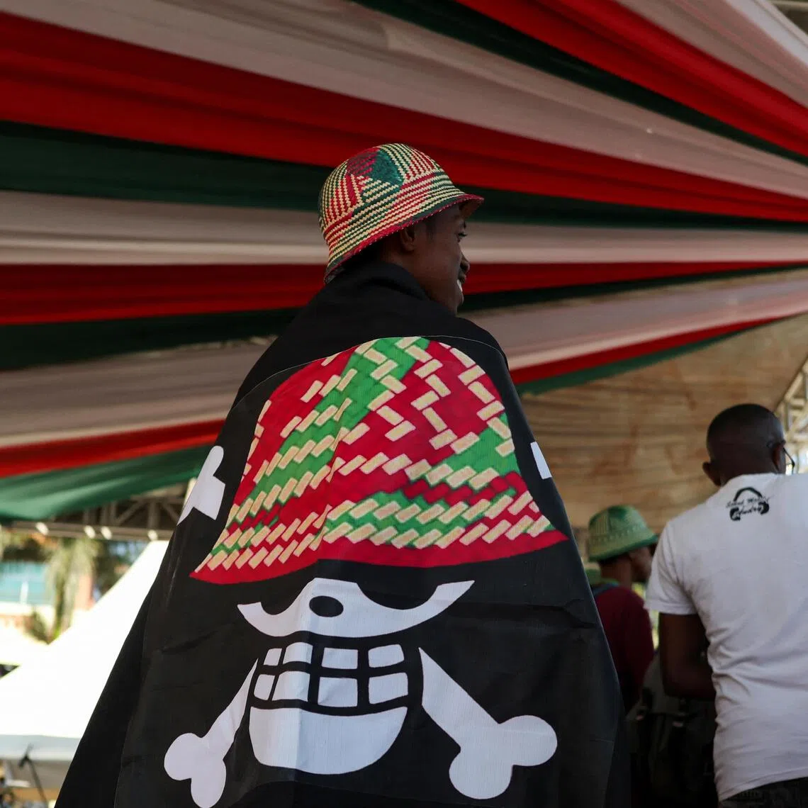 A protester covers himself with a banner featuring a Malagasy version of the logo from the popular Japanese manga One Piece, a symbol adopted by Gen Z protest movements worldwide.