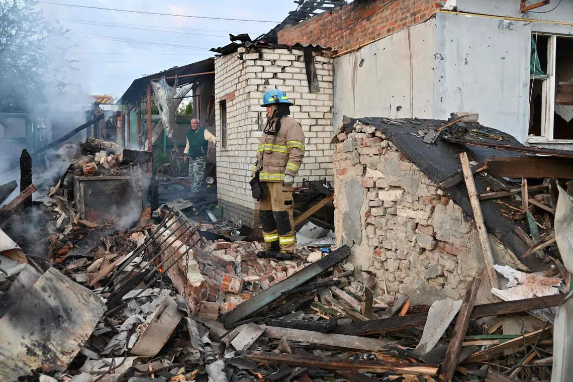 Firefighters clear debris from private houses in the suburbs of Kharkiv destroyed by the attack of Russian drones, on May 21, 2024. AFP