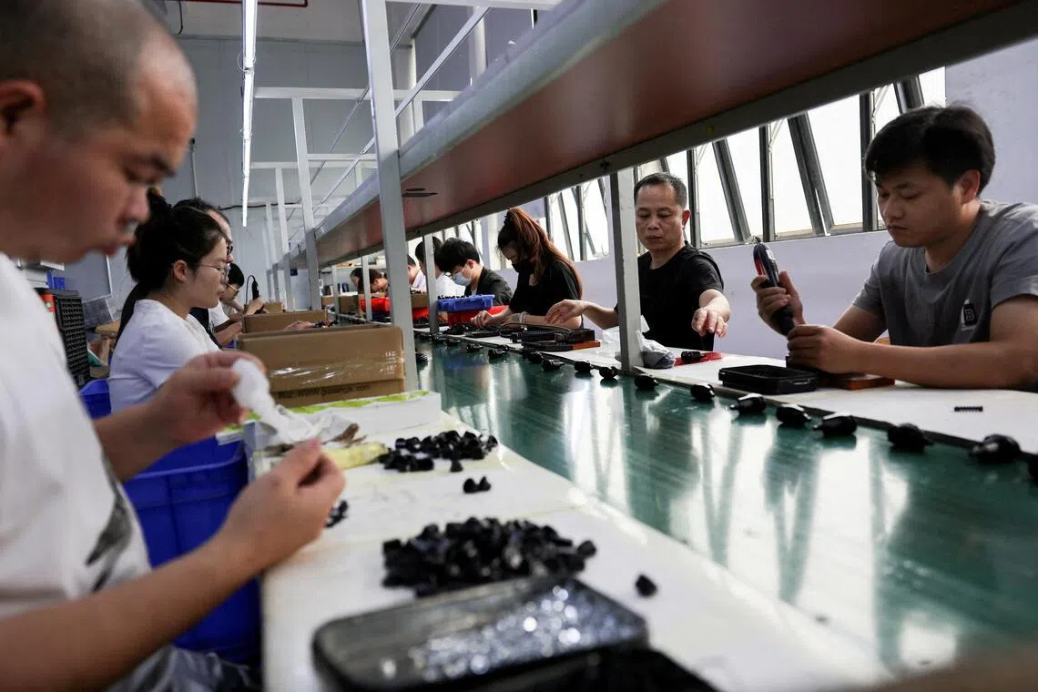 Employees work at an assembly line producing car smartphone holders at a plastic accessories factory in Dongguan, China, on April 2.