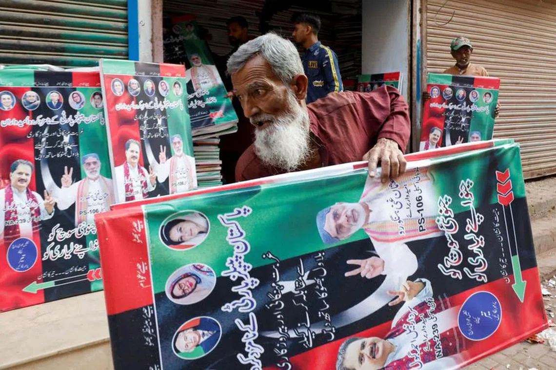 A worker carries campaign posters of a political party to decorate the area, ahead of general elections, in Karachi, Pakistan January 23, 2024. REUTERS/Akhtar Soomro