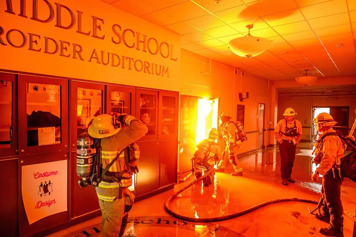 Firefighters preparing to fight flames from inside Eliot Arts Magnet Middle School auditorium as the school burns during the Eaton fire in Los Angeles county, on Jan 8, 2025. 