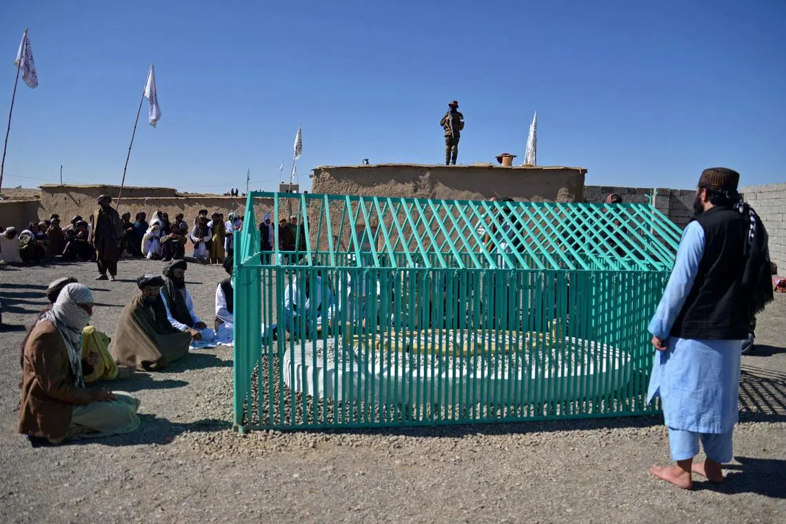 Members of the Taliban sit next to the tomb of late Afghan Taliban leader Mullah Omar, at Omarzo in Suri district of Zabul province on November 7, 2022. - The Taliban on November 6 revealed the final resting place of the movement's founder, Mullah Omar, whose death and burial they kept secret for years. Rumours surrounding Omar's health and whereabouts circulated for years after the Taliban were kicked out of power in 2001 by a US-led invasion, and they only admitted in April 2015 that he had died two years earlier. 