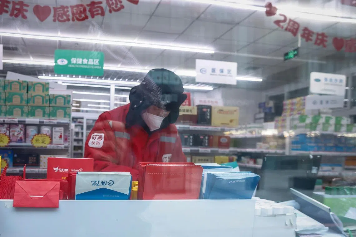 A delivery rider prepares medicine at a drug store in Beijing, China, on Jan 3, 2023.