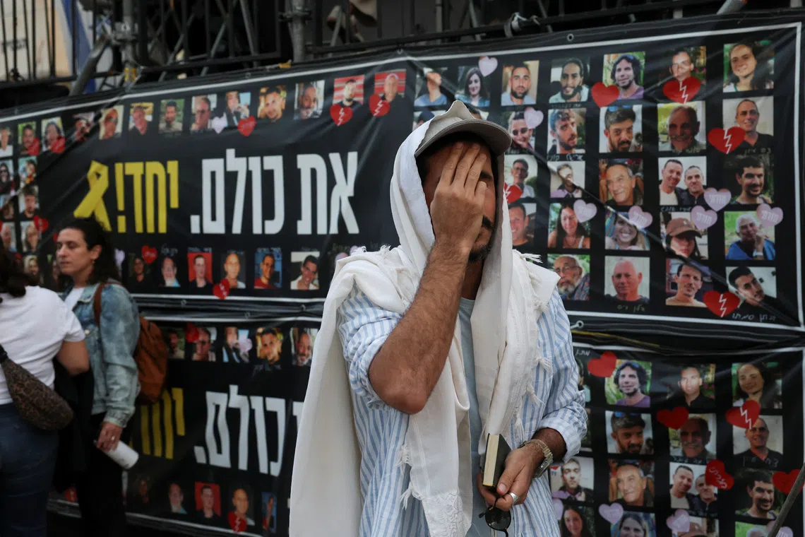 A man prays as people gather at \"Hostages Square\" to await the expected return of Israeli hostages, who have been held in Gaza since the deadly October 7, 2023 attack by Hamas, as part of a prisoner-hostage swap and a ceasefire deal between Israel and Hamas, in Tel Aviv, Israel, October 13, 2025. REUTERS/Ronen Zvulun