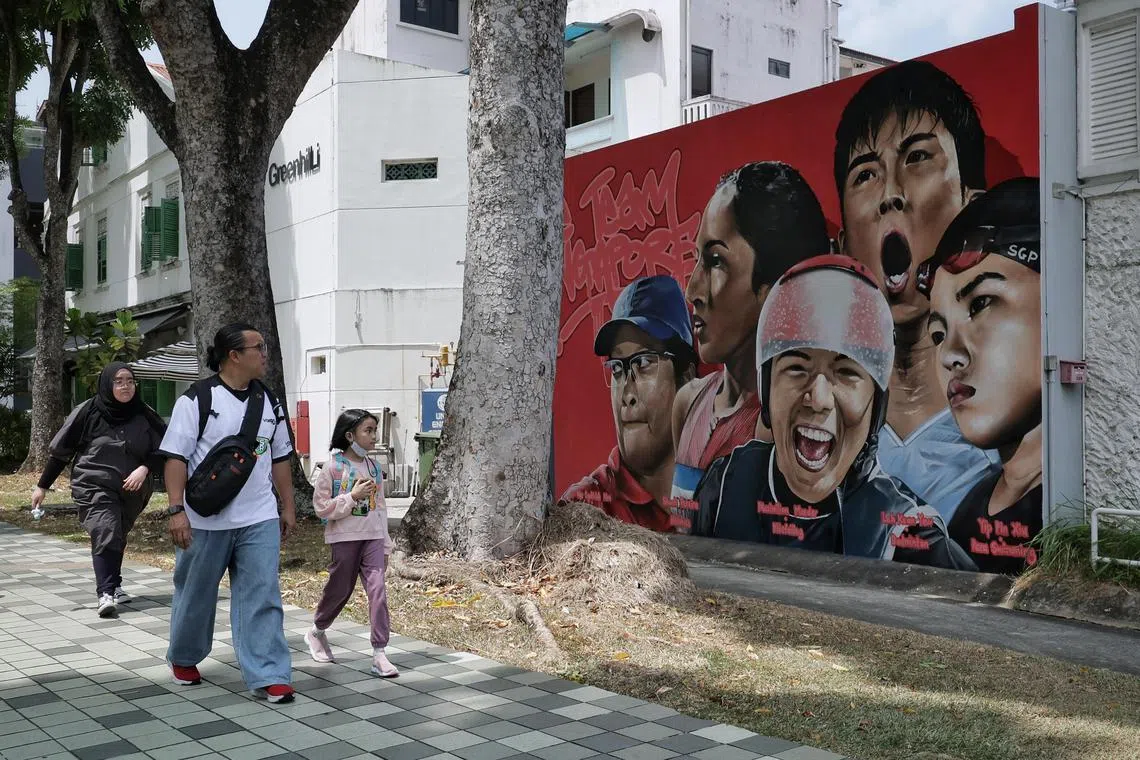 Passers-by at Kampong Glam looking at a mural, which features Singapore's Paris 2024 athletes on July 26.