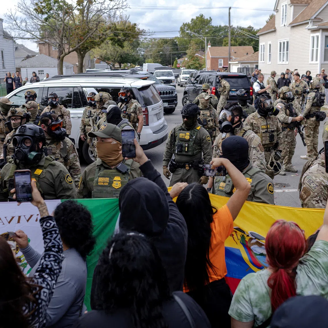 FILE PHOTO: Federal agents stand guard as community members gather near a car crash site where agents detained a man on Chicago?s South Side, in Chicago, Illinois, U.S., October 14, 2025, after U.S. President Donald Trump ordered increased federal law enforcement presence to assist in crime prevention.  REUTERS/Jim Vondruska/File Photo