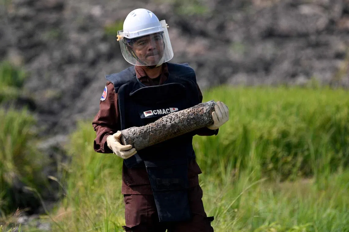 This photo taken on February 11, 2025 shows a deminer from the Cambodian Mine Action Centre (CMAC) carrying an unexploded ordnance (UXO) that was unearthed by a worker during irrigation work in Svay Rieng province. Parts of Cambodia are still littered with unexploded ordnance from decades of conflict, and US President Donald Trump's decision to freeze virtually all American aid has seen many long-running projects to clear the deadly debris grind to a halt. (Photo by TANG CHHIN Sothy / AFP) / To go with 'CAMBODIA-US-POLITICS-LANDMINE-AID,FOCUS' by Suy SE