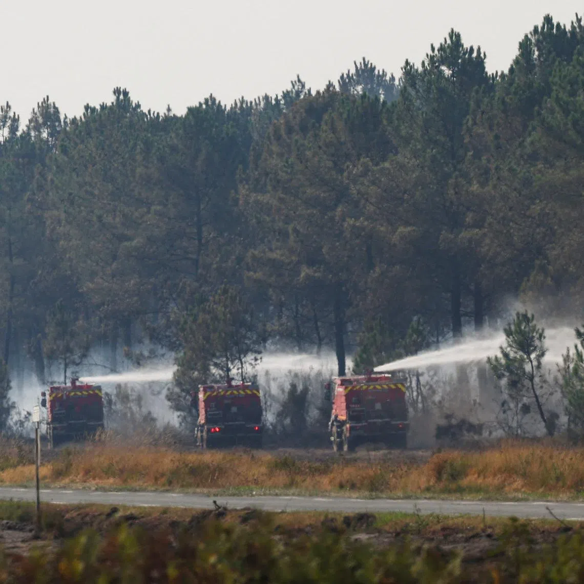 Firefighting vehicles work to extinguish a fire inside a military base during a wildfire in France.