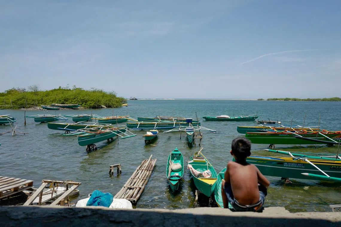 A child watches over fishing boats tied to shore at Gabu Norte village, while a no-sail zone policy was temporarily imposed in Laoag City, northern Philippines on May 7, 2024 during the annual Philippines-United States war games. 