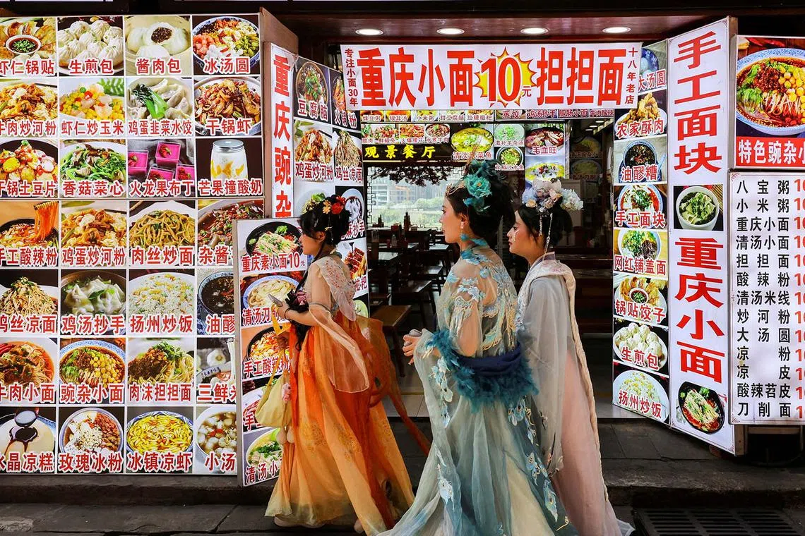 People in traditional Chinese attire walking at Hongyadong Folk Custom Scene Area in Chongqing, China, June 11, 2025. 