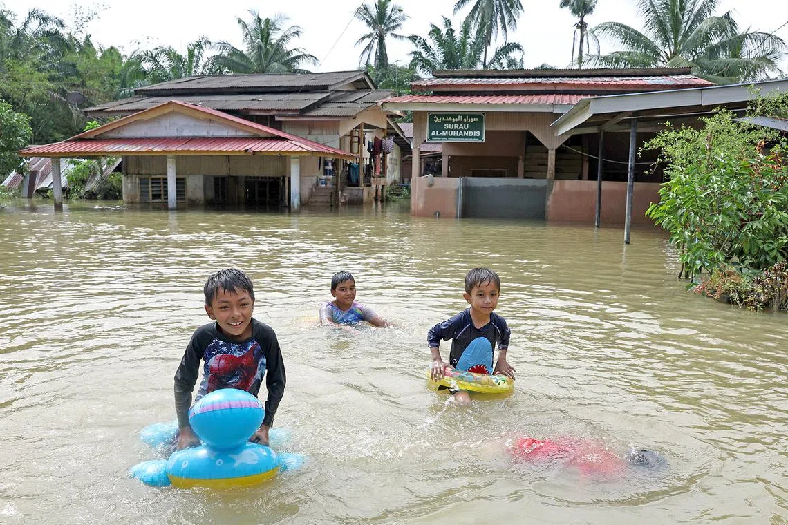 Children playing near their houses that are still flooded following the recent overflowing of the Golok River in Rantau Panjang on Dec 28, 2023.