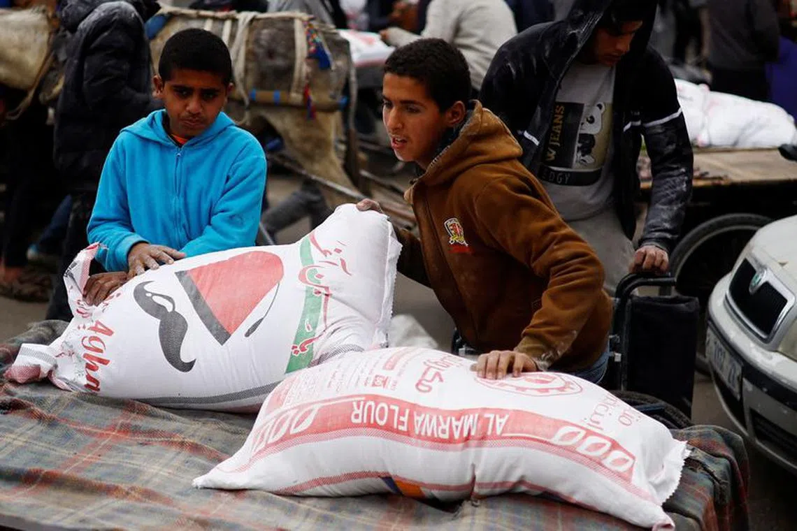 A Palestinian boy arranges bags of flour distributed by the United Nations Relief and Works Agency (UNRWA), amid the ongoing conflict between Israel and Hamas, in Rafah in the southern Gaza Strip January 29, 2024.  REUTERS/Ibraheem Abu Mustafa
