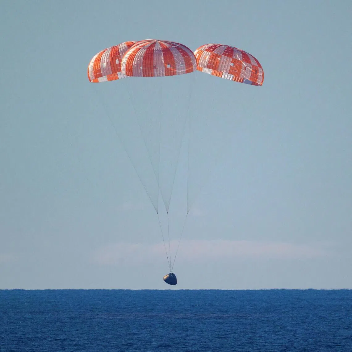 The Artemis II capsule splashes down somewhere in the Pacific Ocean.
