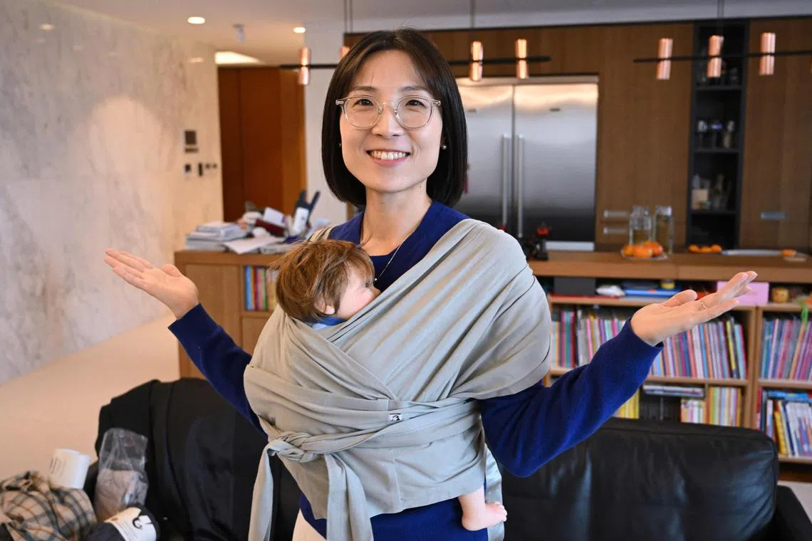 This picture taken on November 29, 2023 shows Erin Lim, CEO of baby products company Konny, demonstrating a baby carrier during an interview with AFP at her home in Seoul. 