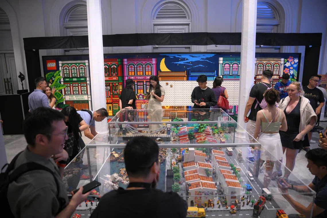 People look at Singapore's largest LEGO Mural (background), set against a LEGO diorama of the Singapore River (foreground),  at the National Museum Singapore on July 17, 2025. The mural was built with over 250,000 LEGO bricks and is part of the Stories of Singapore: Building Our Heritage, Brick by Brick showcase. The mural was officially recognised by the Singapore Book of Records on the same day. Visitors will get access to a total of 528 plates made up of various LEGO bricks, and are invited to add the final bricks to this record-breaking mural.