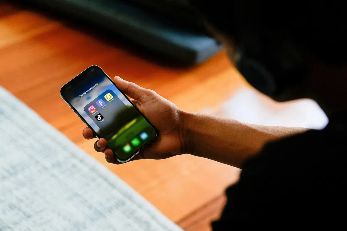 A high school student poses with his mobile phone showing his social media applications in Melbourne, Australia, November 28, 2024. REUTERS/Asanka Brendon Ratnayake