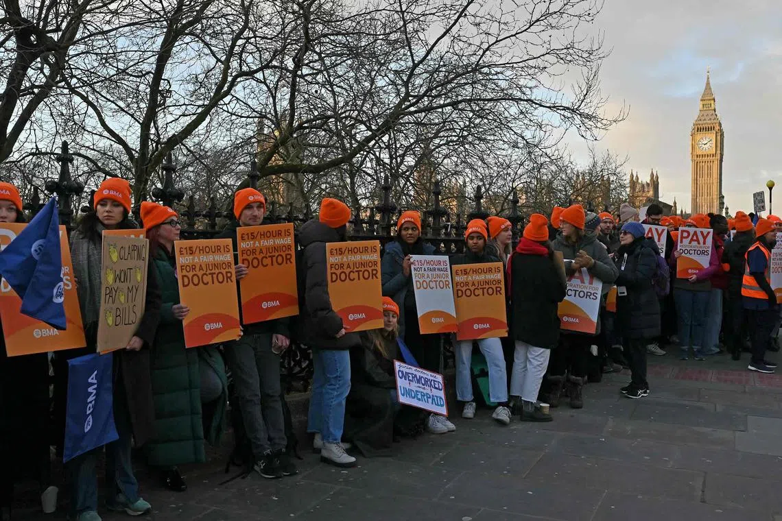 Doctors hold placards calling for better pay, as they stand on a picket line outside St Thomas' Hospital in central London on January 3, 2024.