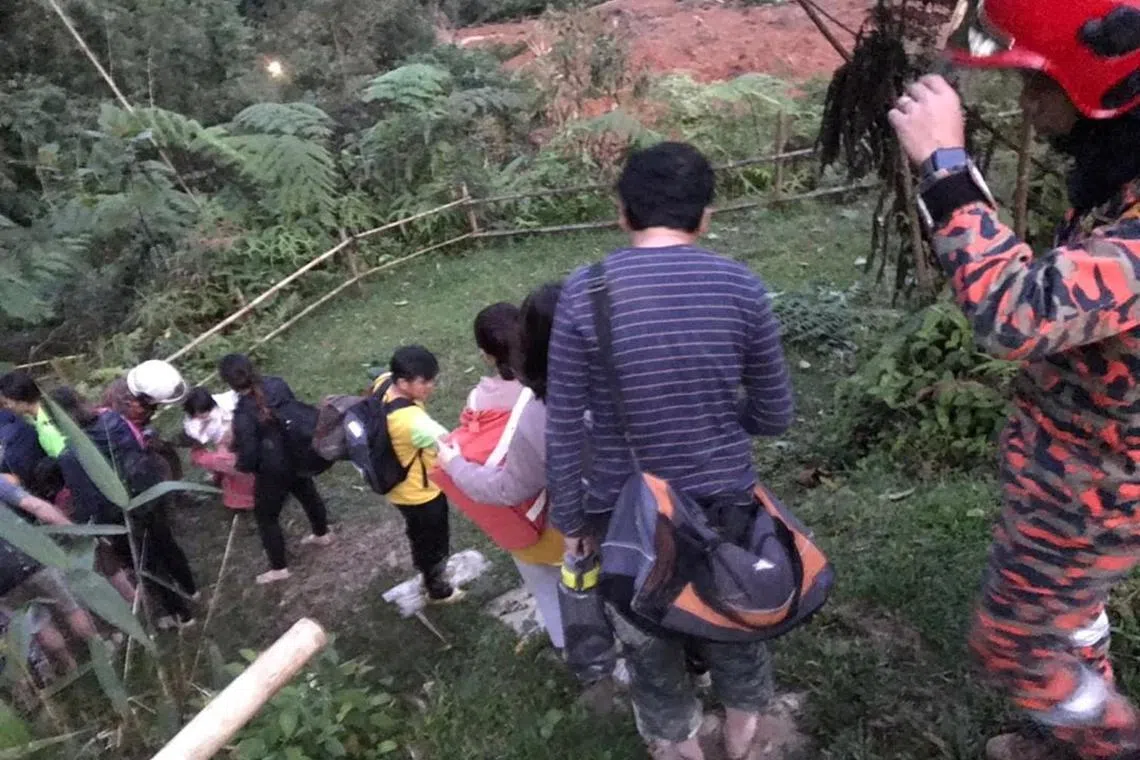Victims walk down a hill during rescue and evacuation operations following a landslide at a campsite in Batang Kali, Selangor state, on the outskirts of Kuala Lumpur, Malaysia, Dec 16, 2022, in this picture obtained from social media. 