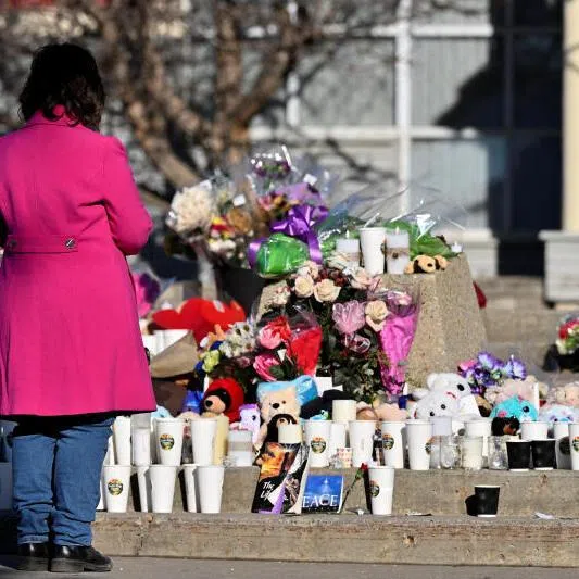 A woman visits a growing makeshift memorial four days after the mass shooting in the town of Tumbler Ridge, British Columbia, Canada, on Feb 14, 2026.