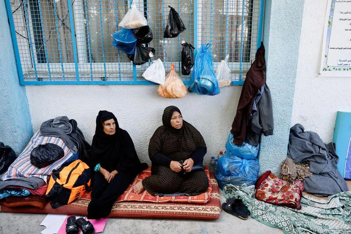 FILE PHOTO: Women sit as Palestinians, who fled their houses amid Israeli strikes, take shelter in a United Nations-run school, after Israel's call for more than 1 million civilians in northern Gaza to move south, in Khan Younis in the southern Gaza Strip, October 20, 2023. REUTERS/Mohammed Salem/File Photo