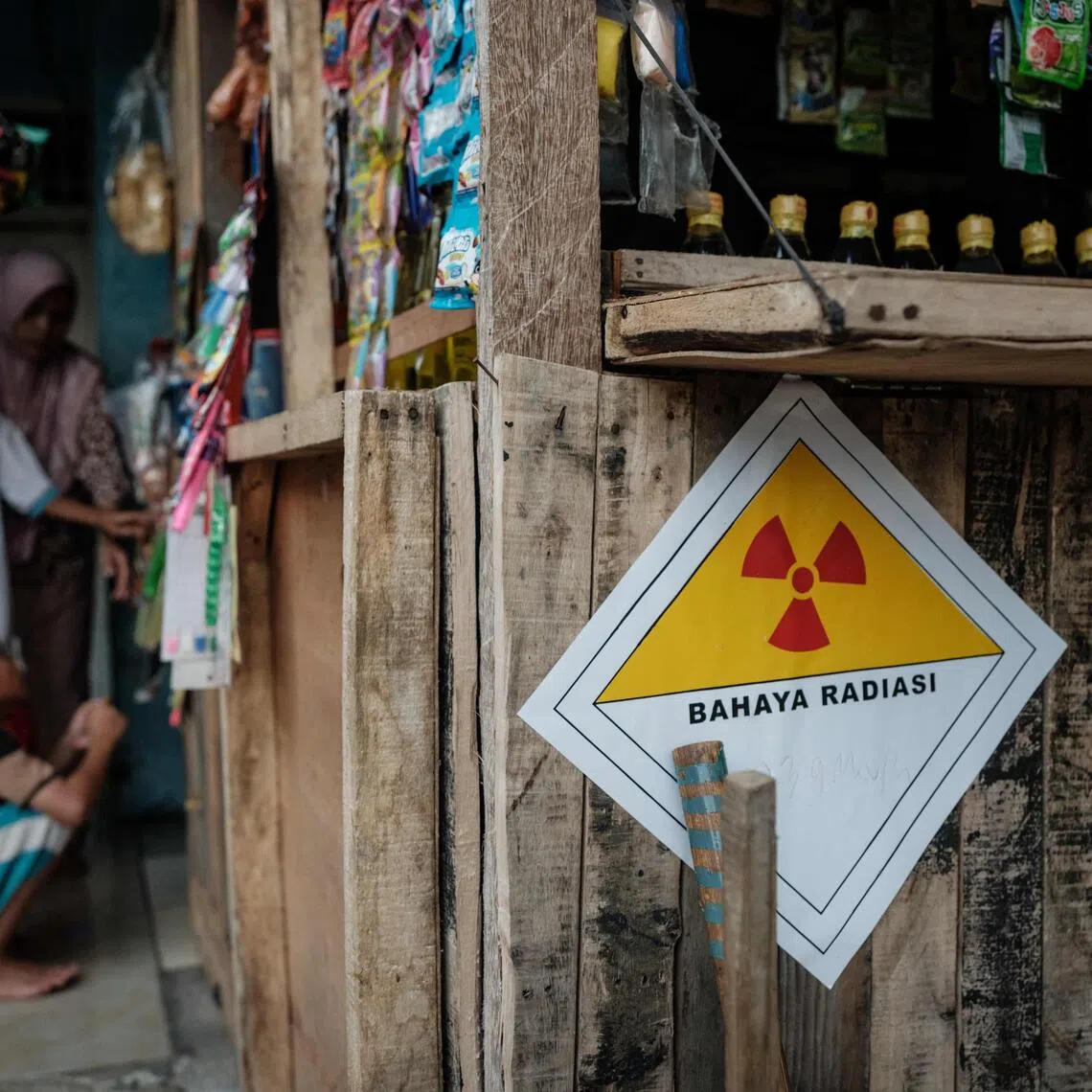 A warning sticker labelled “Danger Radiation” with a handwritten note showing “23.9 microsieverts per hour” is seen on the wall of a kiosk in front of a house next to the Modern Cikande Industrial Estate, where the radioactive isotope Caesium 137 was detected, in Sukatani, Banten province on October 13, 2025. An Indonesian task force found traces of radioactivity in 22 facilities at an industrial zone near the capital, weeks after US authorities recalled potentially contaminated frozen shrimp. (Photo by Yasuyoshi CHIBA / AFP)