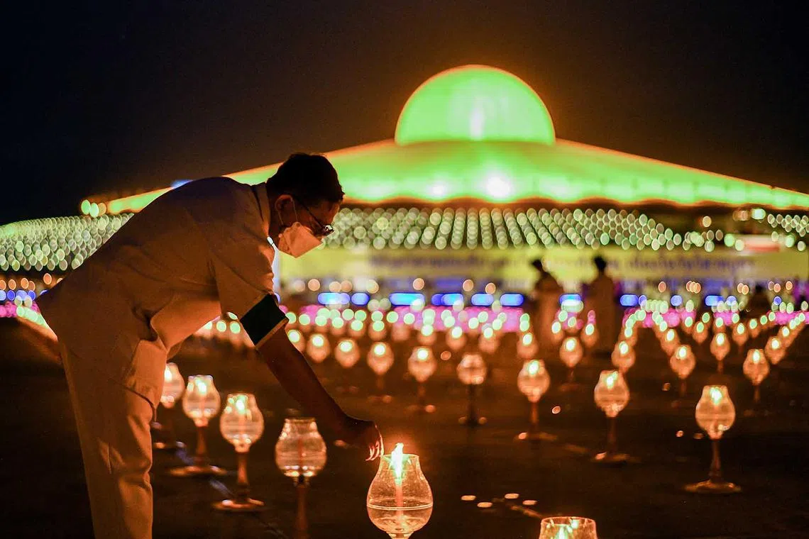 A man lights up a candle light during a ceremony commemorating Vesak Day, an annual celebration of Buddha's birth, enlightenment and death, at the Wat Phra Dhammakaya temple in Pathum Thani province outside Bangkok, Thailand, June 3.