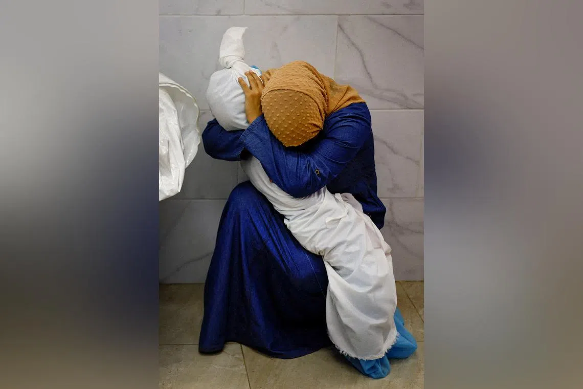 Palestinian woman Inas Abu Maamar embraces the body of her 5-year-old niece Saly, who was killed in an Israeli strike in Gaza on Oct 17, 2023.