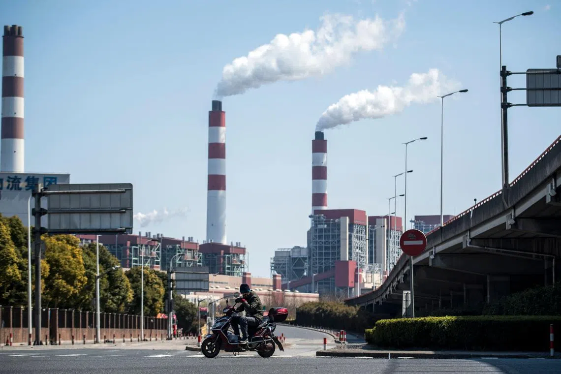 A man riding his scooter near a coal power plant in Shanghai on March 6, 2017.