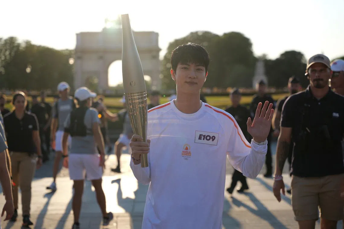 BTS singer Jin carrying the Paris Olympics torch in Paris on July 14.