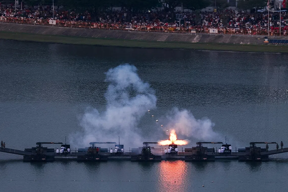 //** MUST INCLUDE “SUNTEC CITY” IN CAPTION OR LOCATION TAG **// One of the 25-pounder howitzers fires during the 21-gun Presidential Gun Salute at Kallang Basin during the National Day Parade 2026 at the National Stadium, as seen from Suntec City on Aug 9, 2026. ST PHOTO: GAVIN FOO
