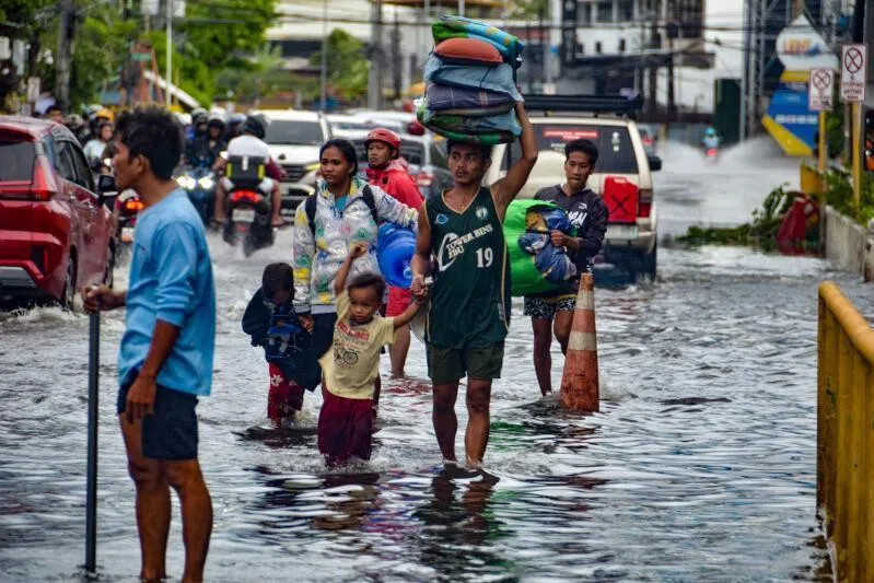 Residents carrying their belongings, wade through a flooded street in Mandaue City, Cebu province on Nov 4.