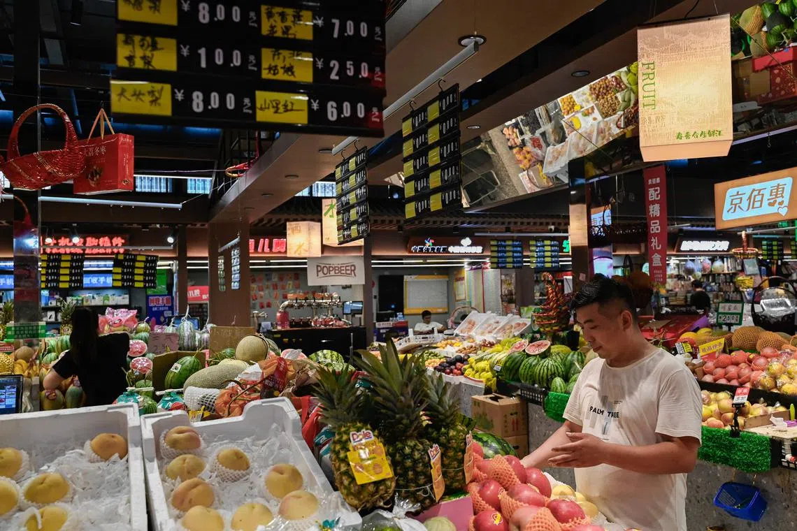 A customer shops for fruits at a market in Beijing on August 9, 2023. (Photo by Pedro PARDO / AFP)