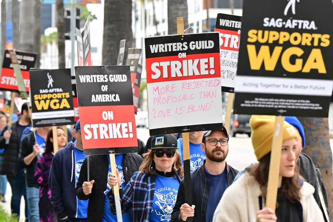 People march with signs on the picket line on day four of the strike by the Writers Guild of America in Hollywood on May 5, 2023. 