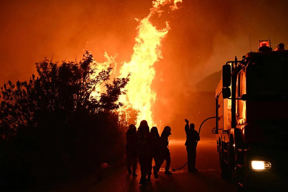 Firefighters working to extinguish a wildfire near the city of Patras, western Greece on Aug 13.