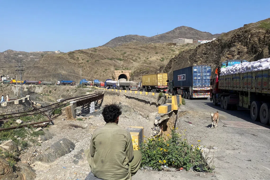 A man sits next to trucks parked at the Torkham border crossing, after Pakistan closed border crossings with Afghanistan, following exchanges of fire between the forces of the two countries, in Torkham, Pakistan, October 12, 2025. REUTERS/Shahid Shinwari