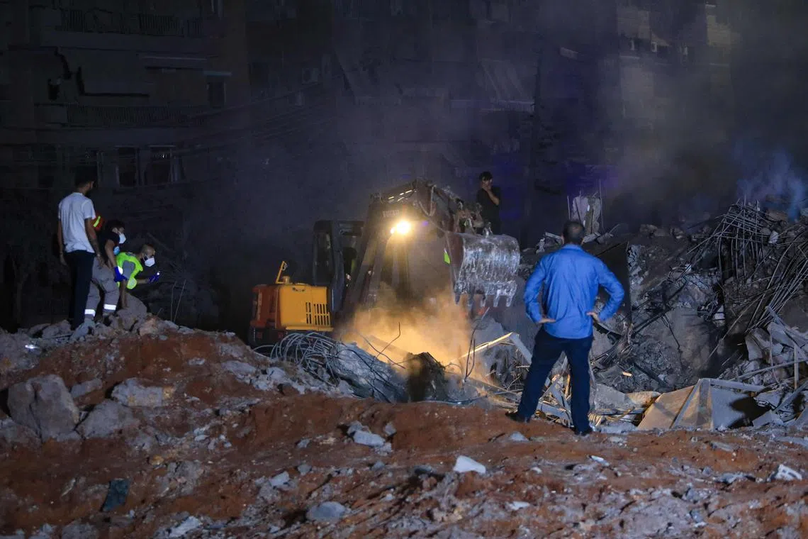 People and first responders stand on the rubble of a building destroyed by an Israeli air strike, in Beirut's southern suburbs on Sept 27.
