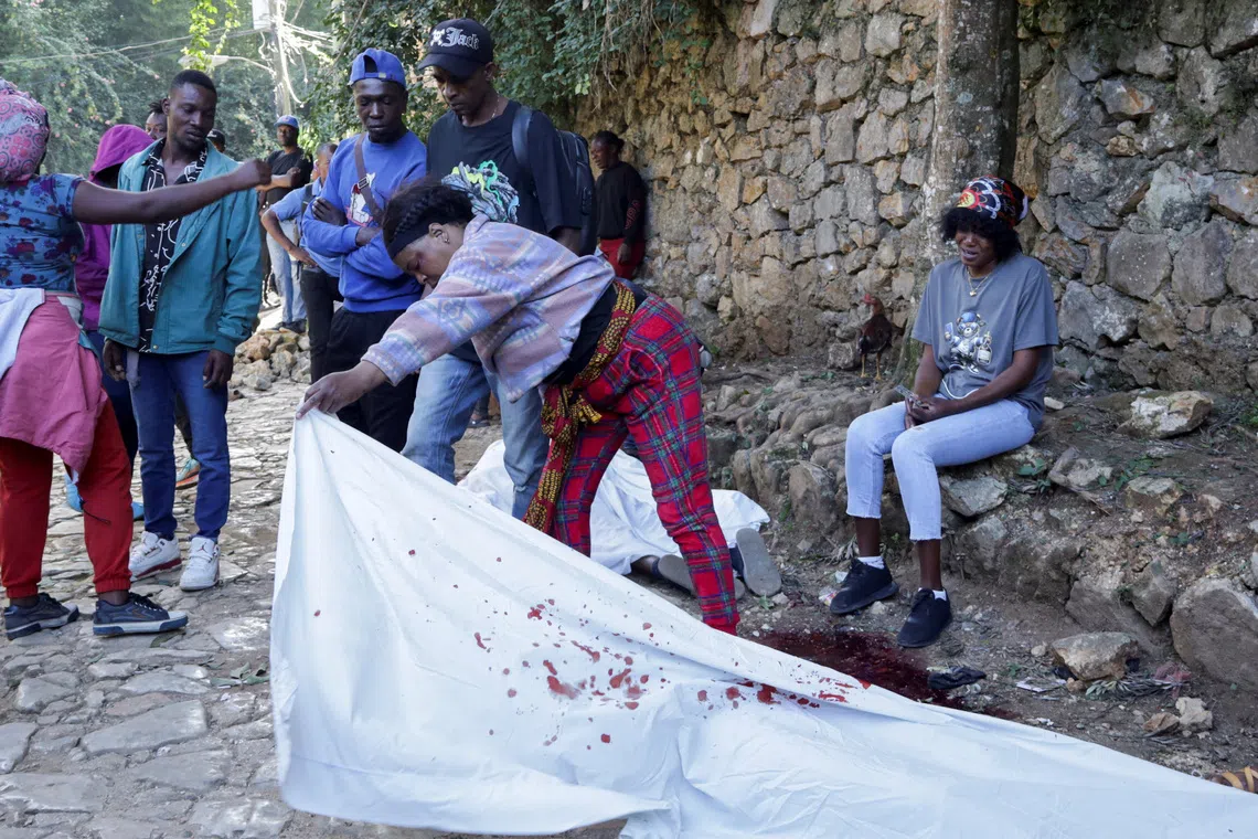 A woman lifts a sheet covering the body of a person killed during an overnight raid by an armed gang, on the outskirts of Port-au-Prince, in Kenscoff, Haiti, August 24, 2026. REUTERS/Fildor Pq Egeder