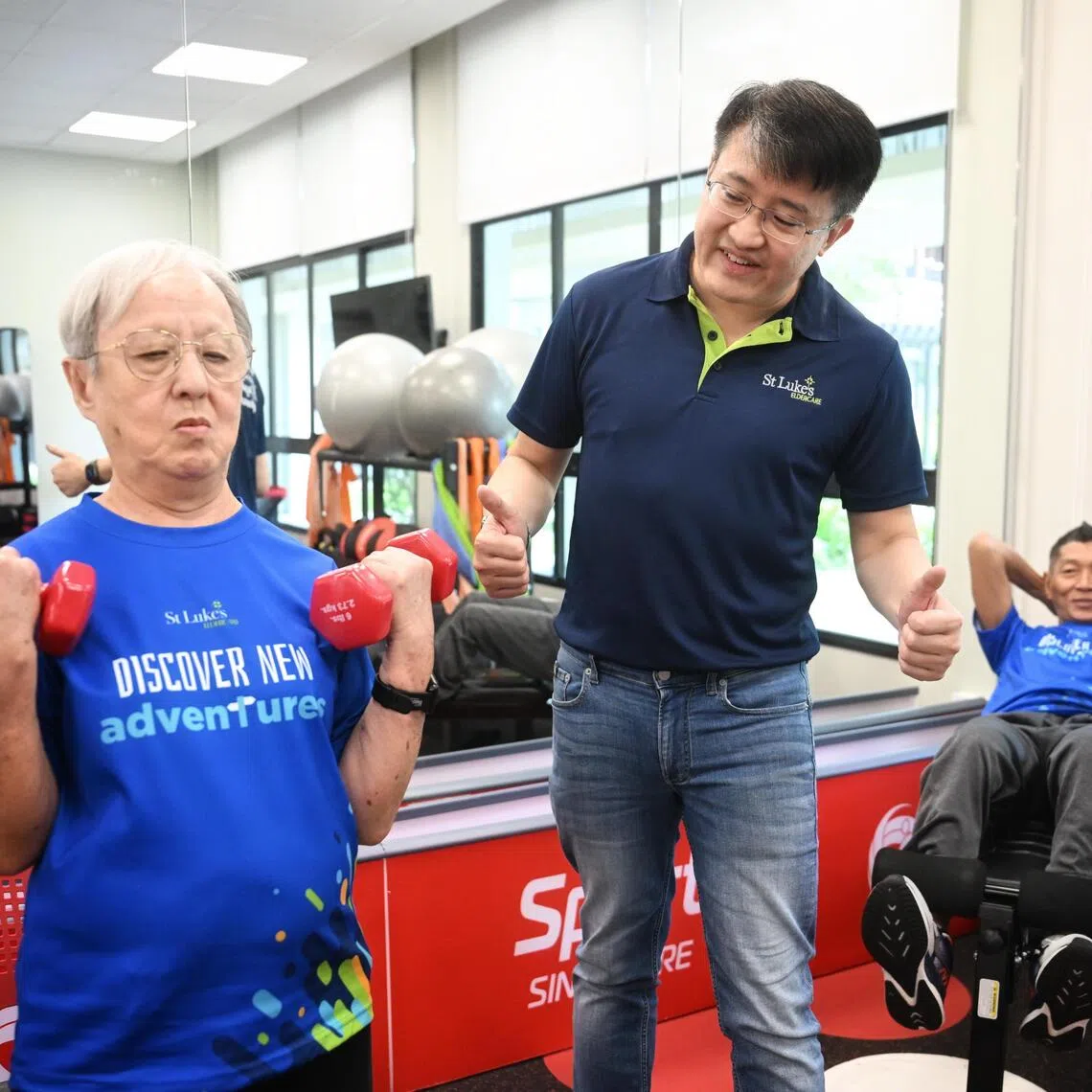 Dr Kenny Tan, Chief Executive Officer of St Luke’s ElderCare, (centre) encouraging Madam Lee Siew Liang, 79 (left) and Mr Jeffrey Tay, 62 (right) as they exercise at the St Luke's ElderCare Active Ageing Centre (Care) @ Northshore on Sept 12, 2025