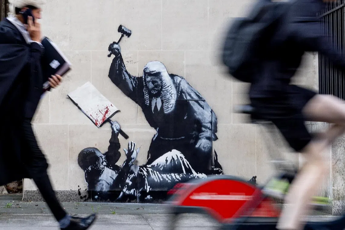 The stencilled mural shows a bewigged judge using a gavel to hit a protester holding a blood-splattered placard.