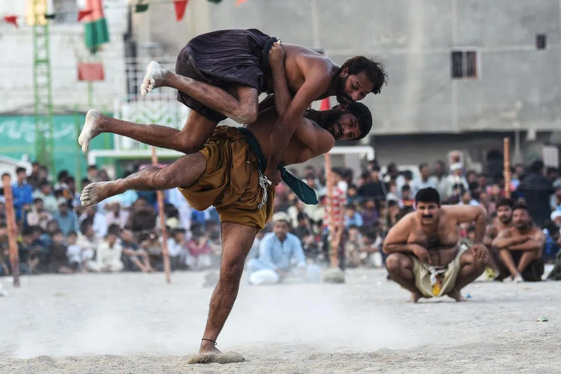 Wrestlers compete in a 'Sindhi Malakhra' wrestling match, a local ancient form of wrestling originated in Pakistan's Sindh region, during a local tournament in Karachi on November 14.