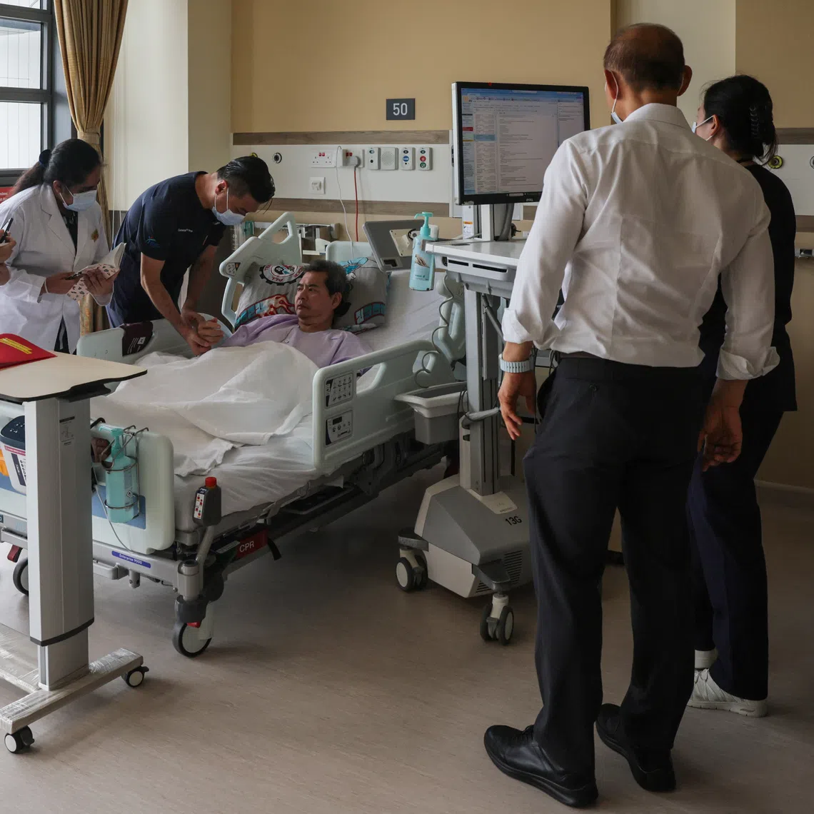 Second-year TCM students from NTU observing Dr Quah Teik Joo as he takes the pulse of stroke patient Tan Kay Chuan.