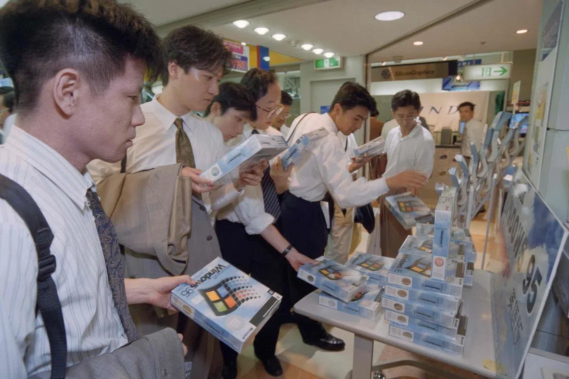 (FILES) Shoppers in Tokyo, gather around imported English versions of Microsoft's Windows 95 software in a computer store on August 25, 1995. Microsoft has been at the heart of computing for half a century, becoming a tech stalwart almost taken for granted as lifestyles embraced the internet. As the Redmond, Washington-based company founded with a vision of putting computers in every home and office celebrates its 50th anniversary on April 4, it looks to boost its fortunes by being a leader in artificial intelligence. (Photo by Kazuhiro NOGI / AFP)