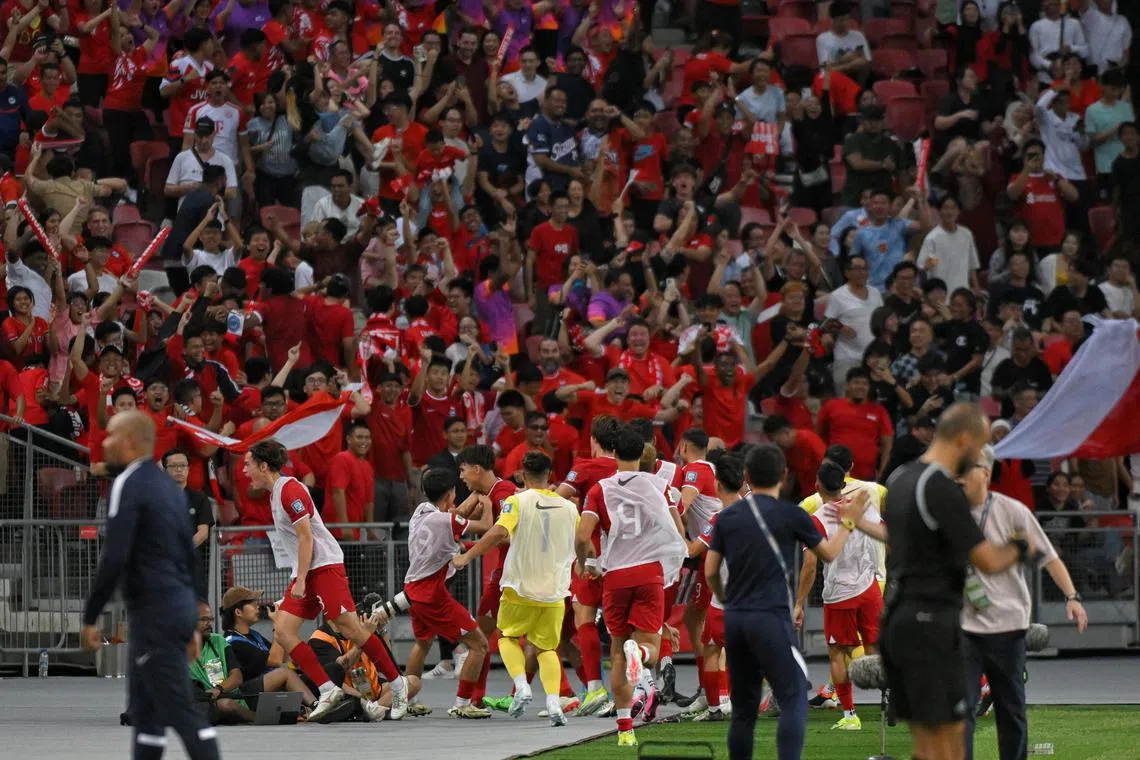 The Singapore football team, including substitutes and backroom staff, celebrate in front of the home team fans after scoring the equalising goal against China during the World Cup 2026 and Asian Cup 2027 R2 qualifiers held at the National Stadium on March 21, 2024.